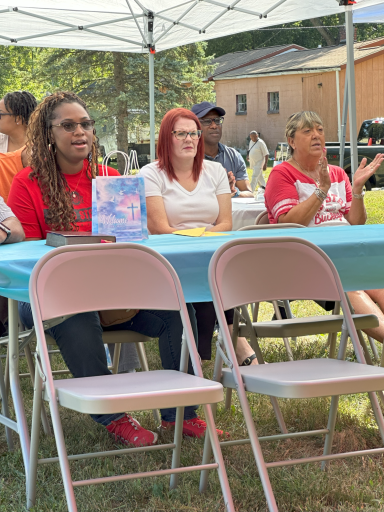 A group of people sitting at a table under a tent, enjoying an outdoor event.