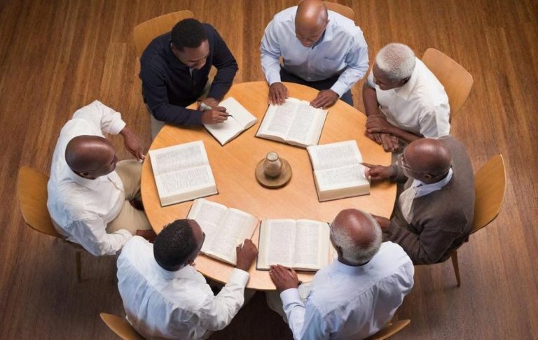 Stock Photo of men gathered around table having a Bible Study