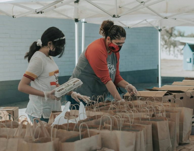 Stock photo of individuals packing food bags for a giveaway.